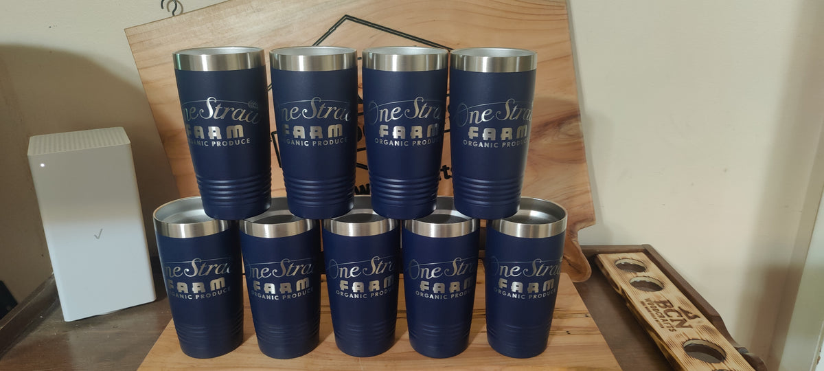 Nine navy blue insulated tumblers with silver stainless steel rims, arranged in two rows on a wooden display stand. Each tumbler features a custom laser-engraved design that reads 'One Sixty SEVEN Farm' with 'One Sixty Seven Farm' below it., polar camel.