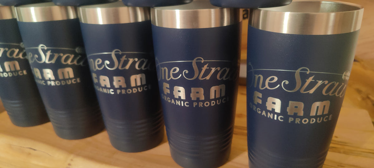 A row of dark navy blue insulated tumblers with stainless steel lids, printed with the logo and text 'One Straight Farm Organic Produce' in white, displayed on a wooden surface., polar camel.