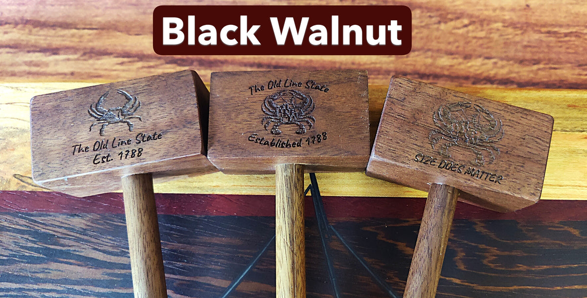 Three wooden mallets with engraved crab designs and text, displayed against a wood-grain background with a 'Black Walnut' label at the top.