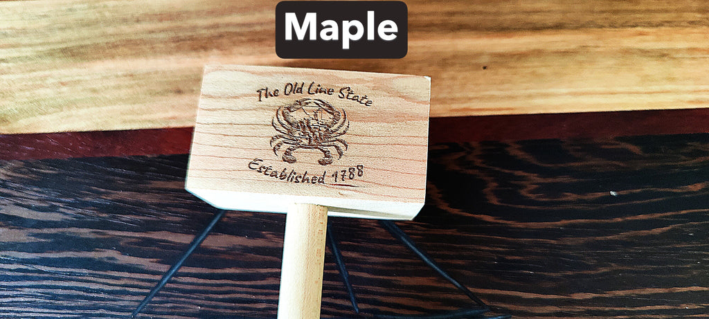 A small wooden sign or plaque on a stand, labeled 'Maple' at the top. The sign is made of light natural wood with a dark engraved emblem and text reading 'The Old Lion State' and 'Established 1788'.